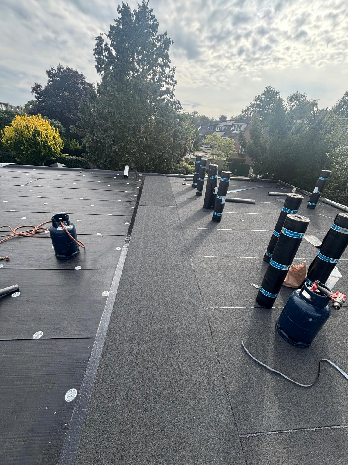 Aanbrengen toplaag bitumen met branders op plat dak Heiloo