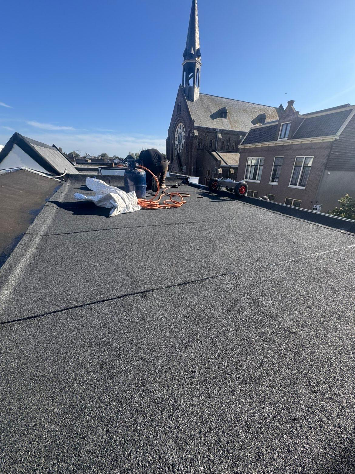 Nieuw bitumen plat dak in Den Helder met zicht op de kerk